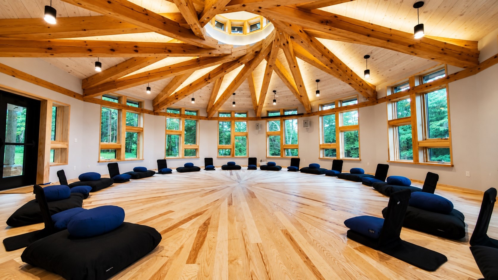 Reciprocal timber-frame roof radiating around a circular skylight in the Soul Fire Farm education building, designed by LEAP Architecture